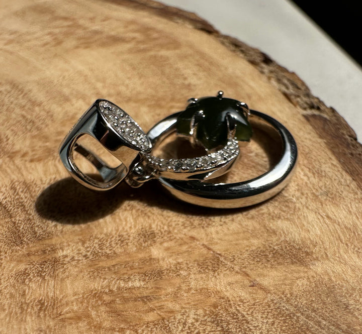 Canadian Jade and Silver Star and Moon Pendant with green jade centerpiece and diamond studded bail on a wood surface