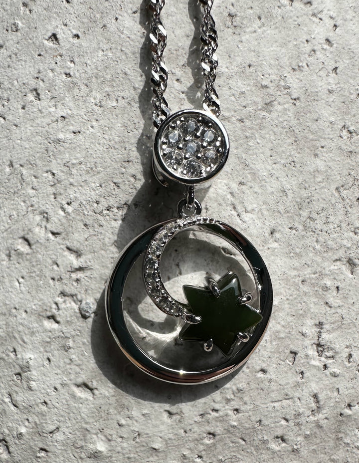 Pendant featuring pavé diamond disk above a crescent moon and green jade star on a silver chain