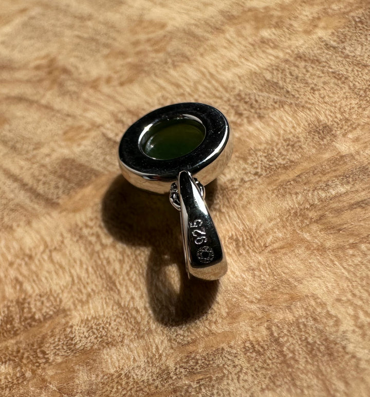 Dainty Silver and Jade Pendant 6mm with green jade cabochon displayed on a textured wood surface.