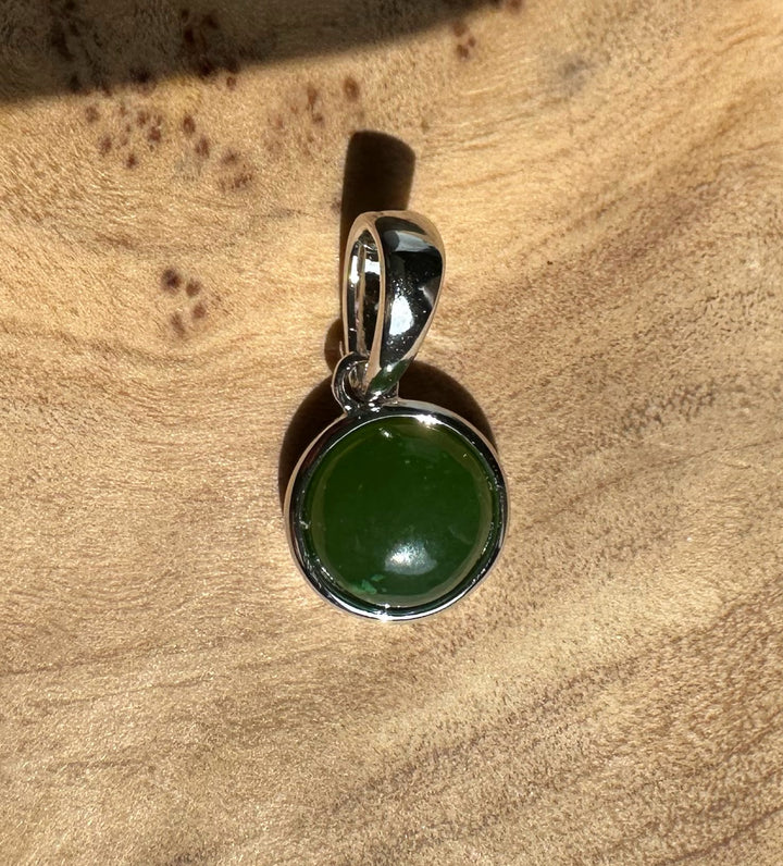 Green jade pendant in a silver bezel with curved bail on a silver chain