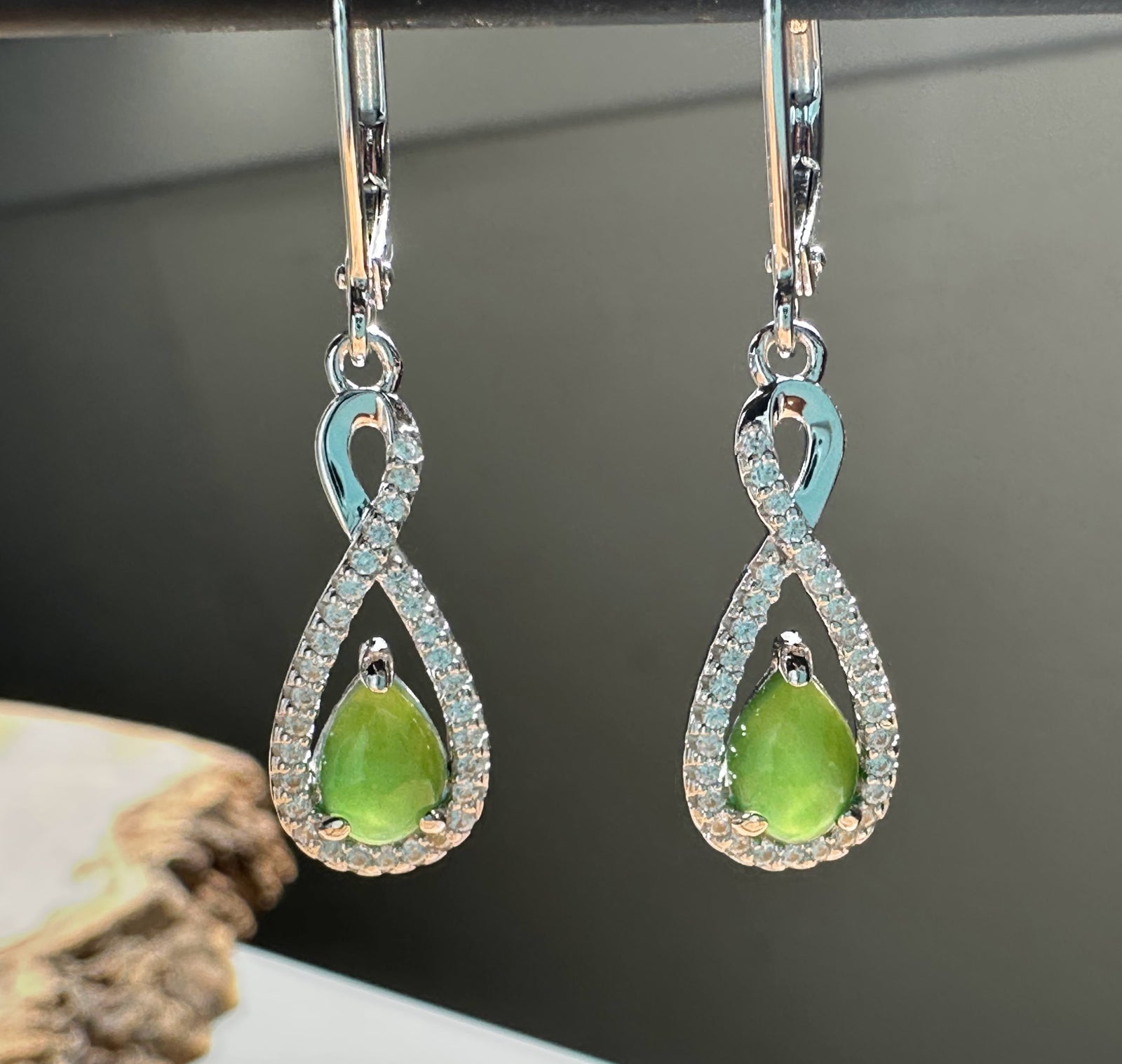 Canadian Jade and Silver Infinity Twist Earrings featuring green jade teardrop drops framed by diamond-studded infinity loops.