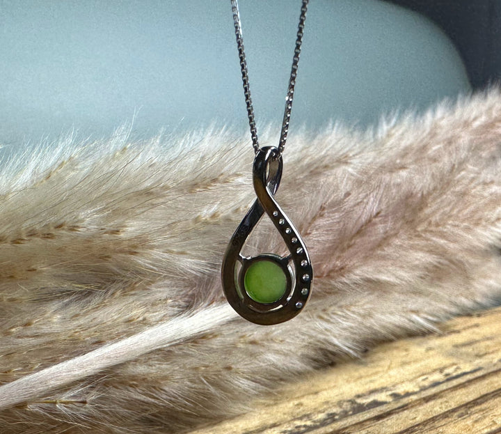 Silver Infinity pendant with a lime green round center stone hanging on a delicate chain