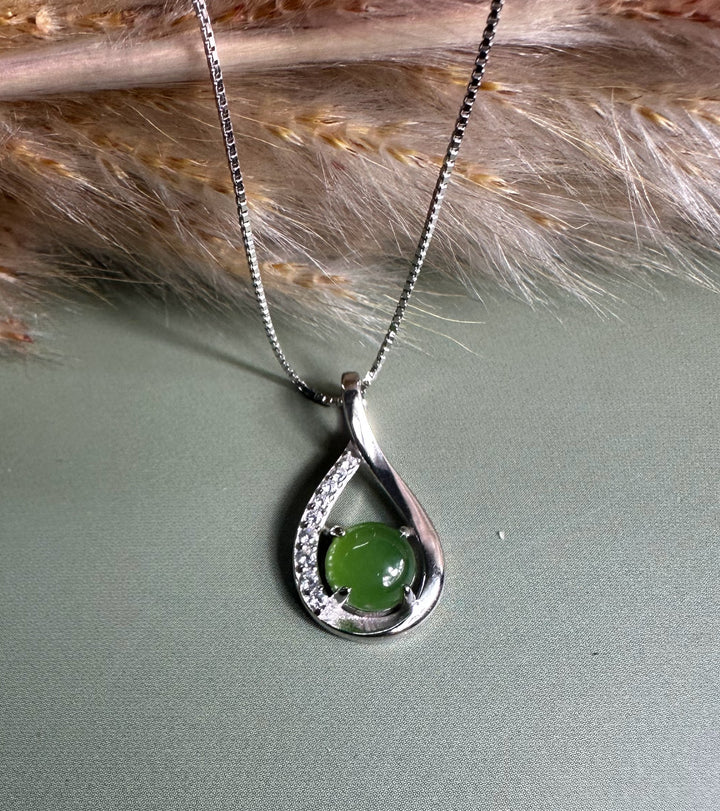 Silver Infinity pendant featuring a green center stone held inside a teardrop shaped frame with diamonds along the inner curve