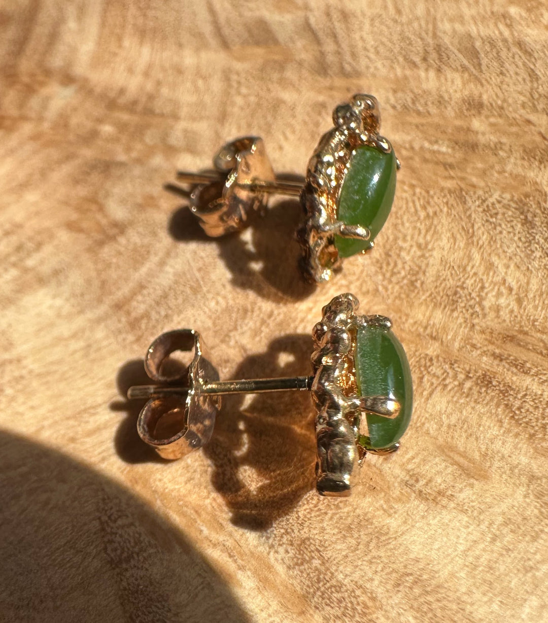 Close-up of vintage jade earring showing a green oval stone in a gold ornate setting with post back.