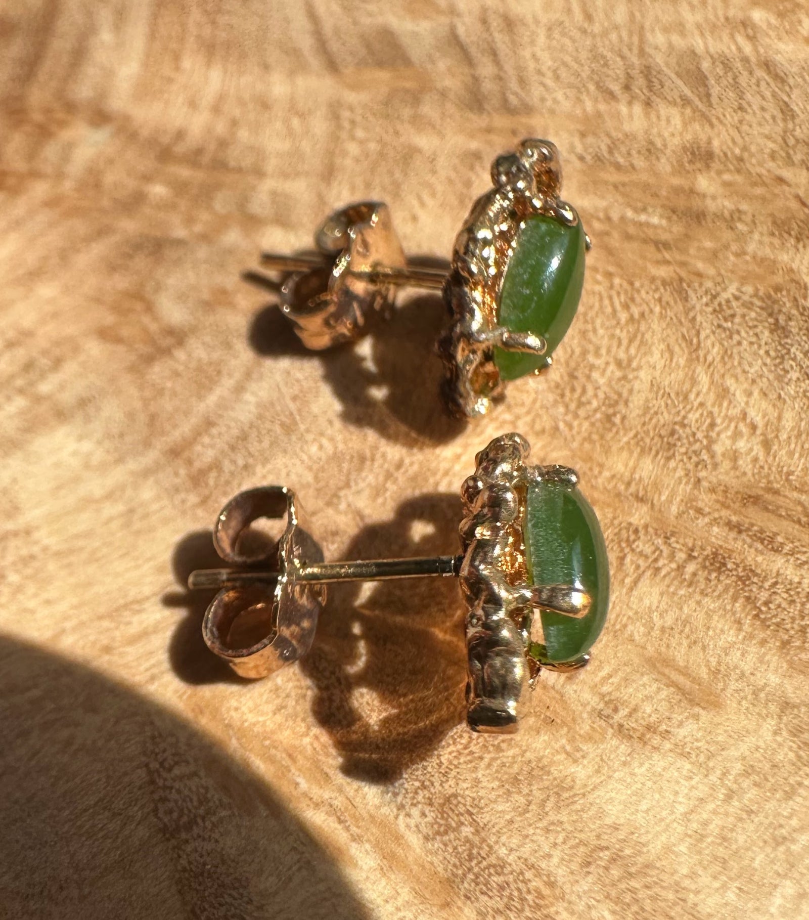 Close-up of vintage jade earring showing a green oval stone in a gold ornate setting with post back.