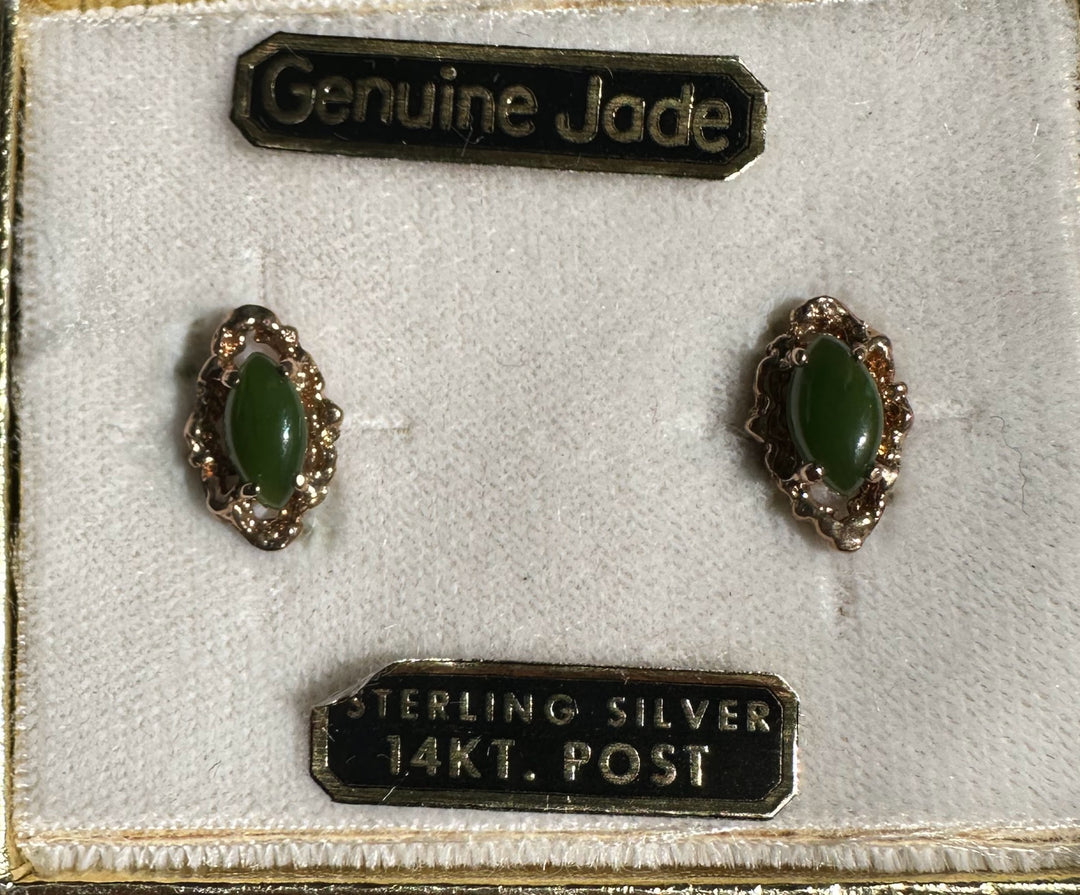 Two vintage green jade earrings with matching gold filigree mounts on a display mat beside a Genuine Jade 14KT Post label