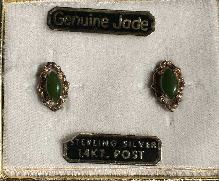 Two vintage green jade earrings with matching gold filigree mounts on a display mat beside a Genuine Jade 14KT Post label
