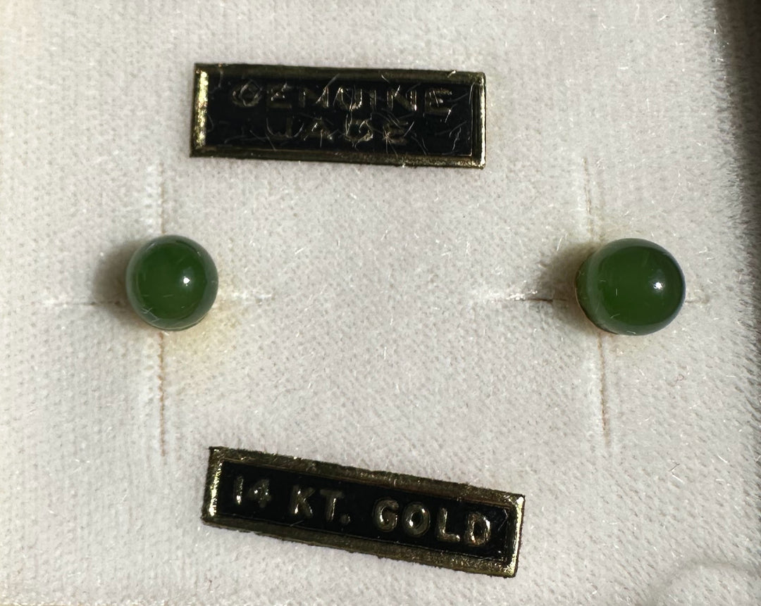 Green jade stud earrings shown with a 14K gold label on pale fabric