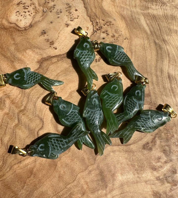 Group of green fish pendants with etched lattice scales and gold bail fittings arranged together