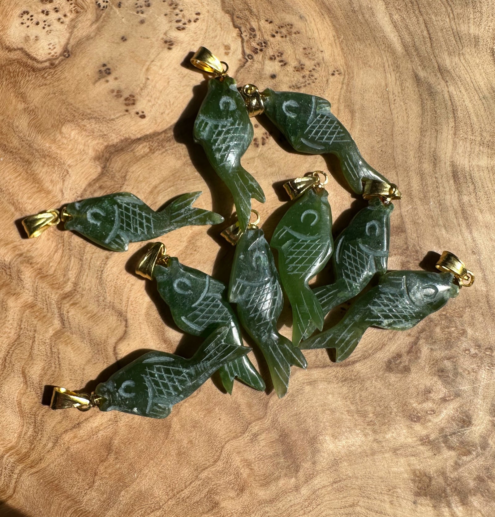 Group of green fish shaped pendants with gold bails and carved scale pattern
