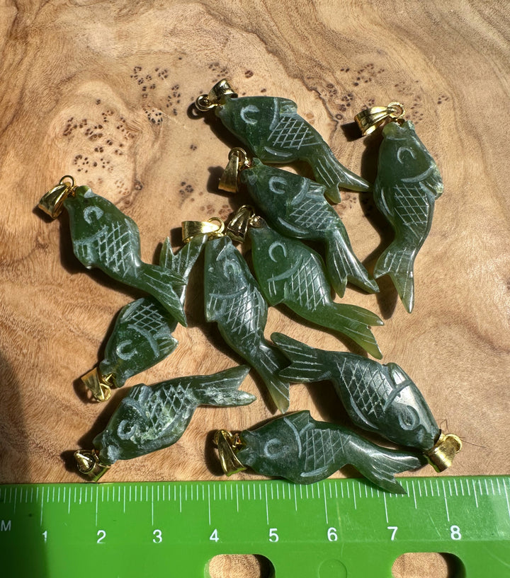 Green fish shaped pendants on wood with a green ruler at the bottom for scale