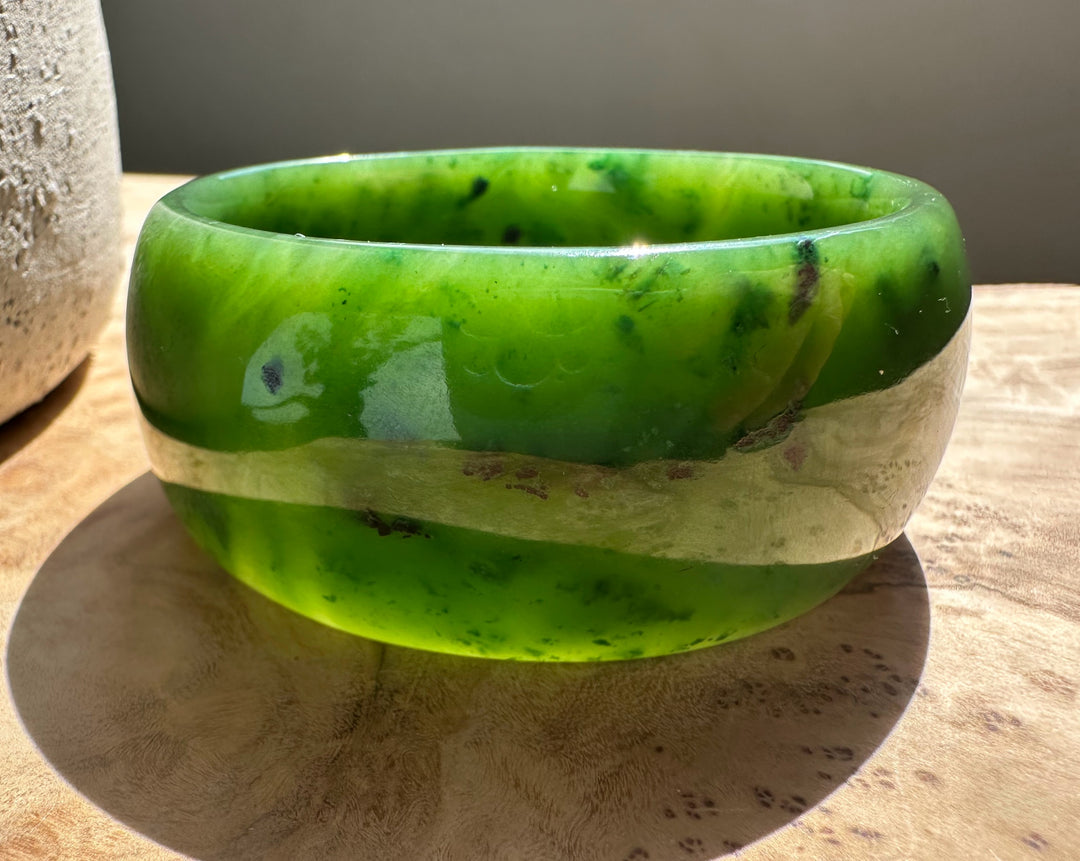 Close-up of the jade bangle showing vivid green color and a pale gray band around the center.