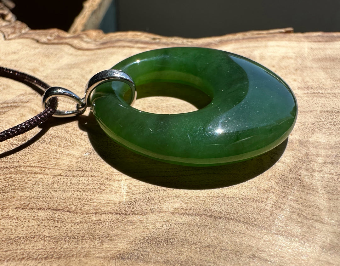 Green jade ring pendant on a wooden surface