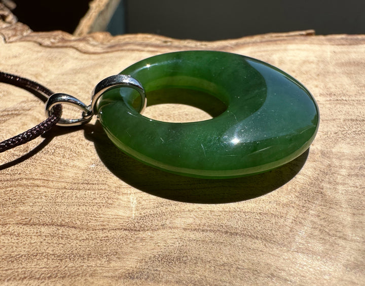 Green jade ring pendant on a wooden surface