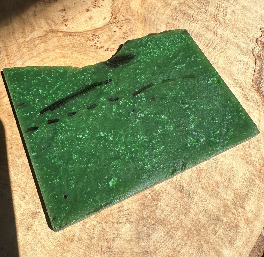A Grade Canadian Cassiar Jade slab weighing 130 grams resting on a wooden surface.