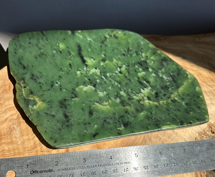 Green jade slab on a wooden surface with a ruler for scale.