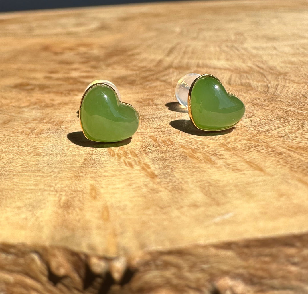 Heart-shaped green jade earrings on a wooden surface