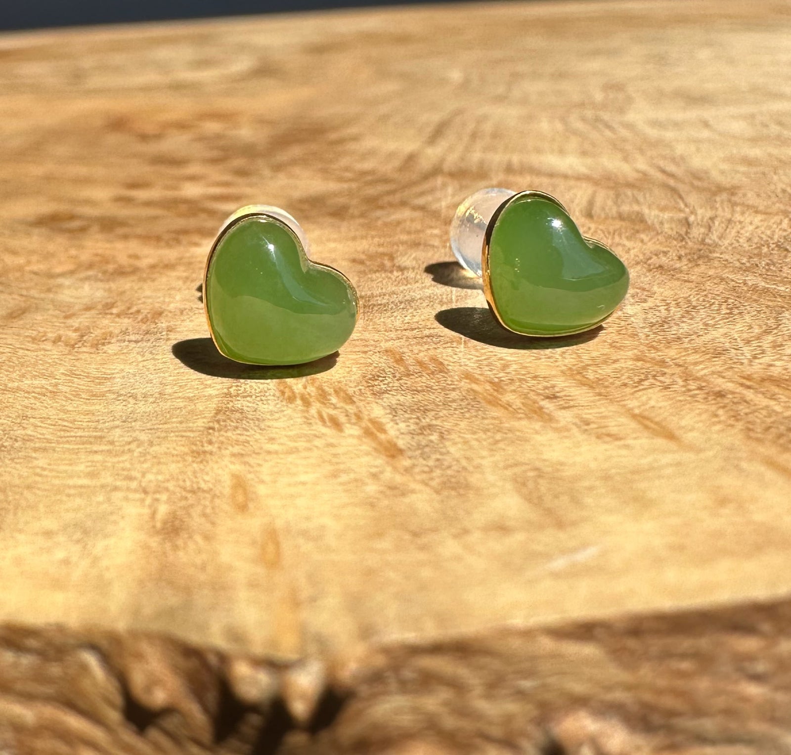 Heart-shaped green jade earrings on a wooden surface