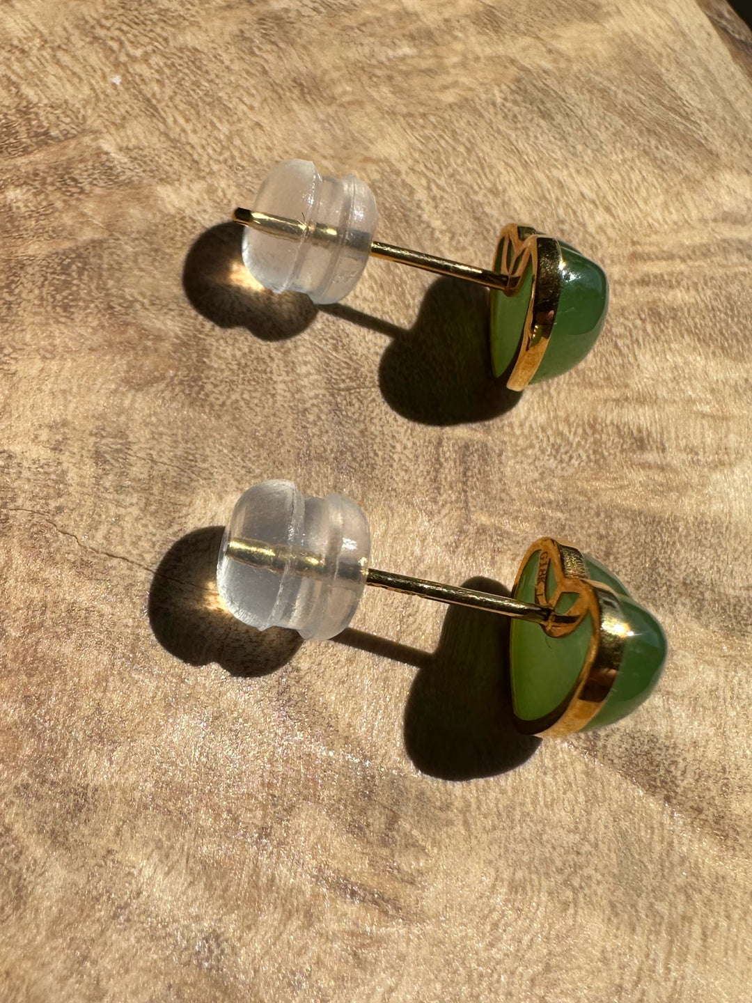 Pair of earrings with green and clear stones on a beige surface