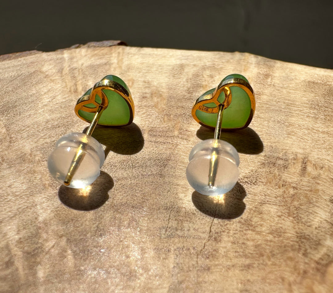 Heart-shaped earrings with green and gold design on a wooden surface
