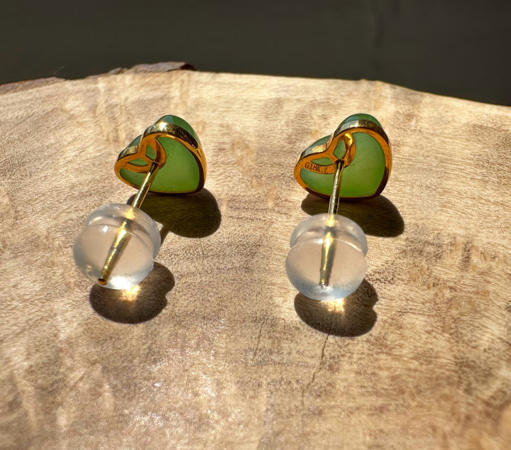 Heart-shaped earrings with green and gold design on a wooden surface