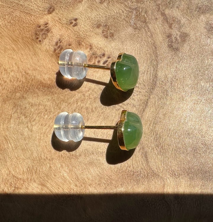 Pair of earrings with green and clear stones on a wooden surface