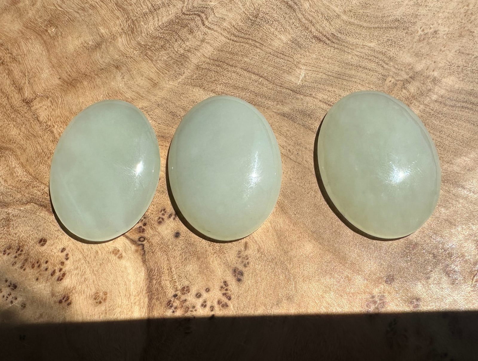 Three light green jade cabs on a wooden surface