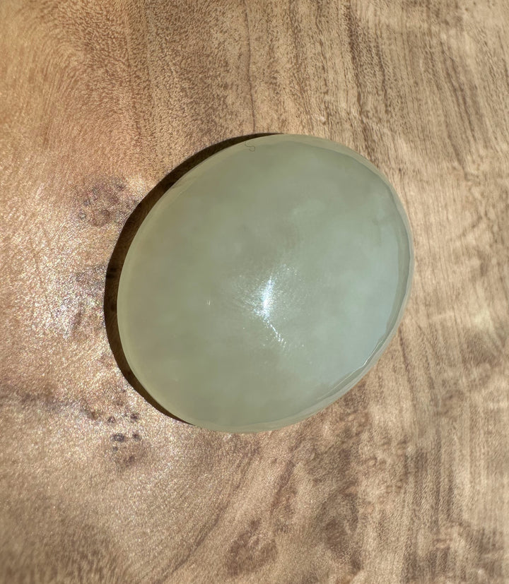 white jade cabochon on a wooden surface