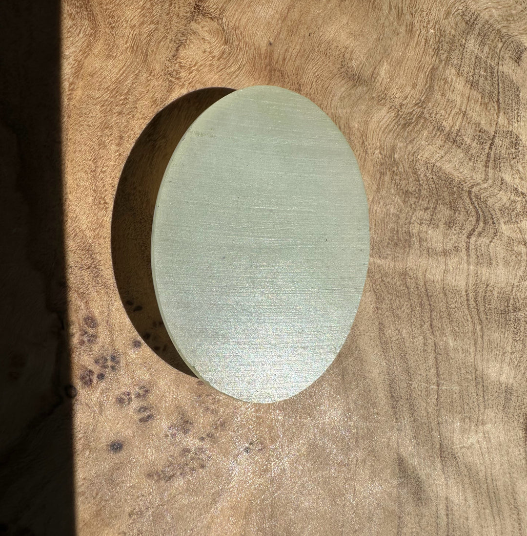 Back side of the jade cabochon on a wooden surface