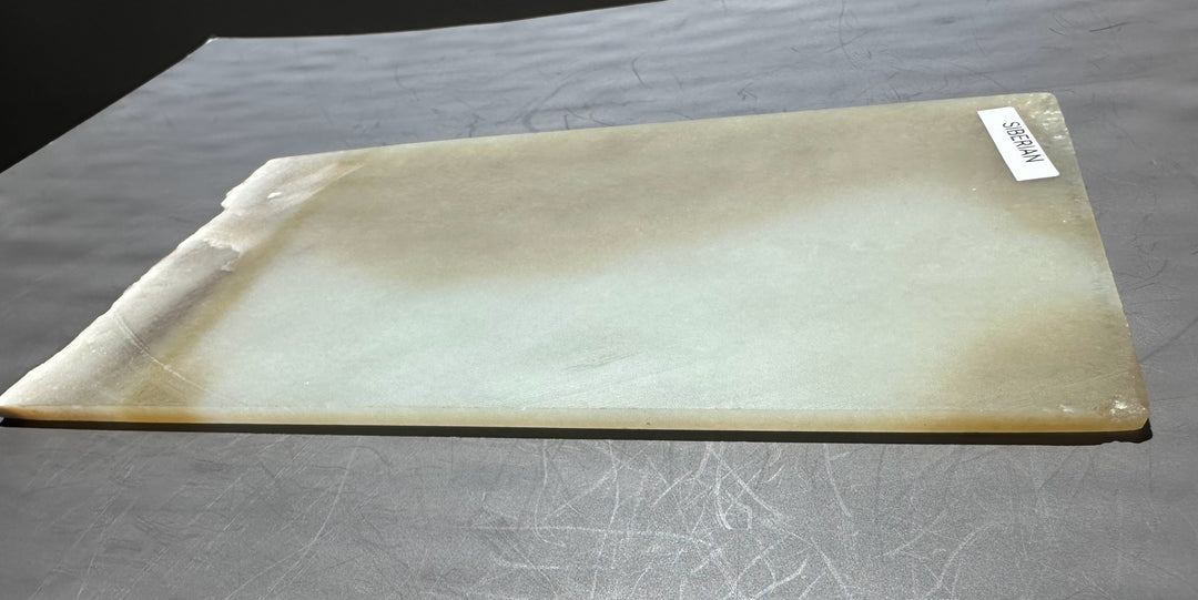 Honey white nephrite jade slab with a chipped left edge and a SIBERIAN label on the surface