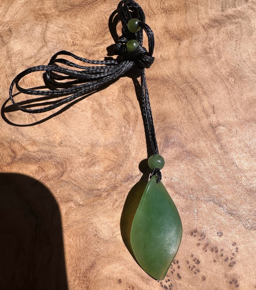 Green pendant necklace on a textured brown surface