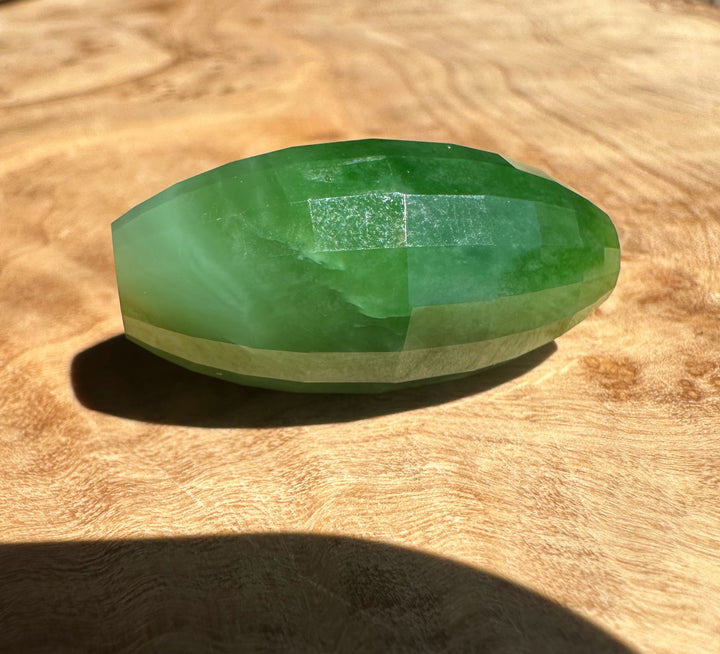Green jade bead on a wooden surface