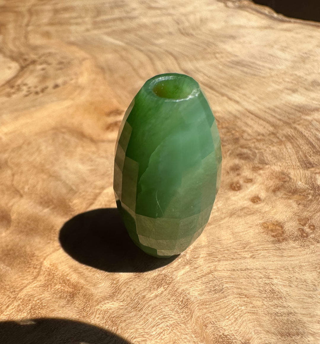 Green stone bead on a wooden surface