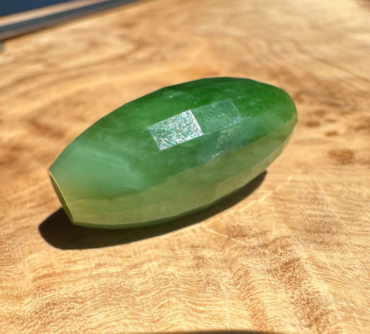 faceted green bead on a wooden surface
