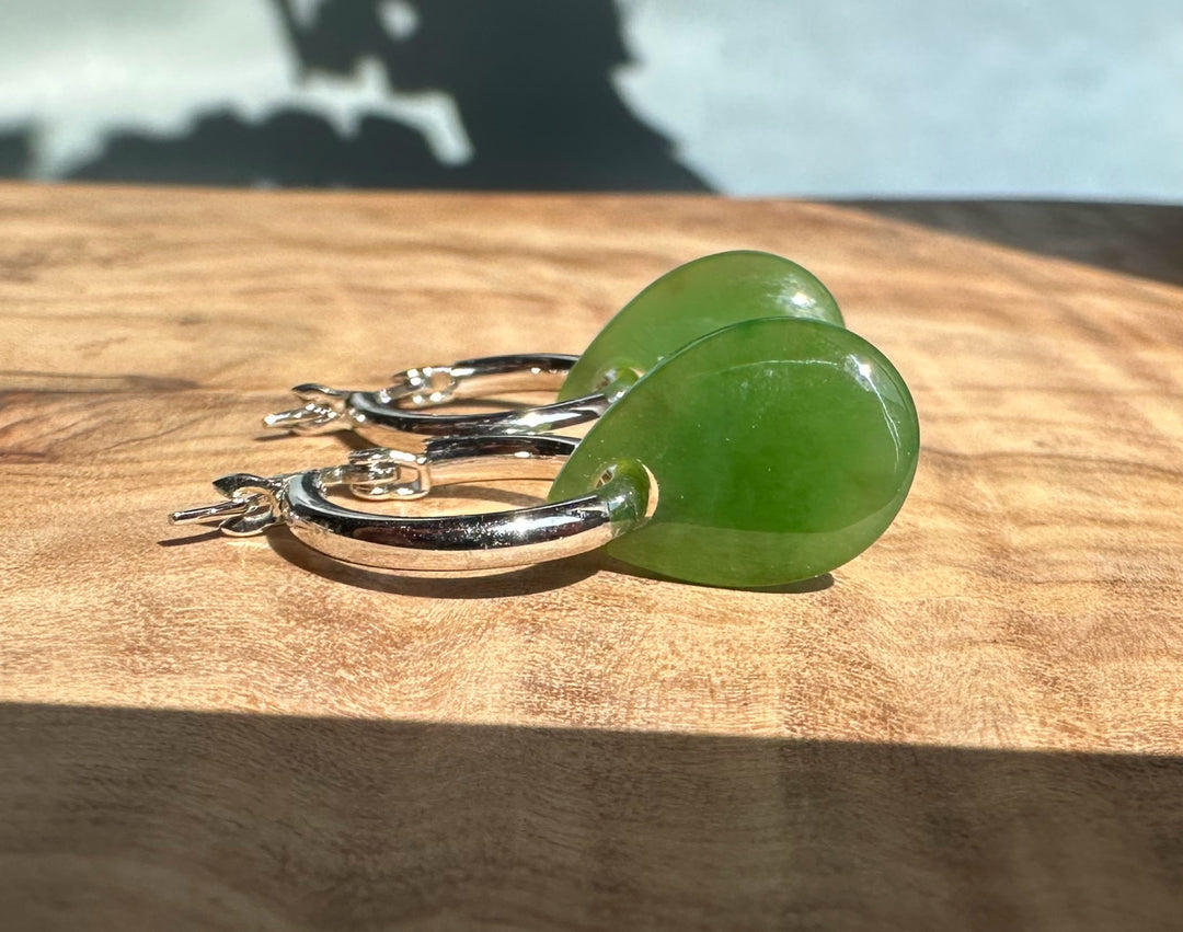 Pair of green jade teardrop earrings on silver hoops.