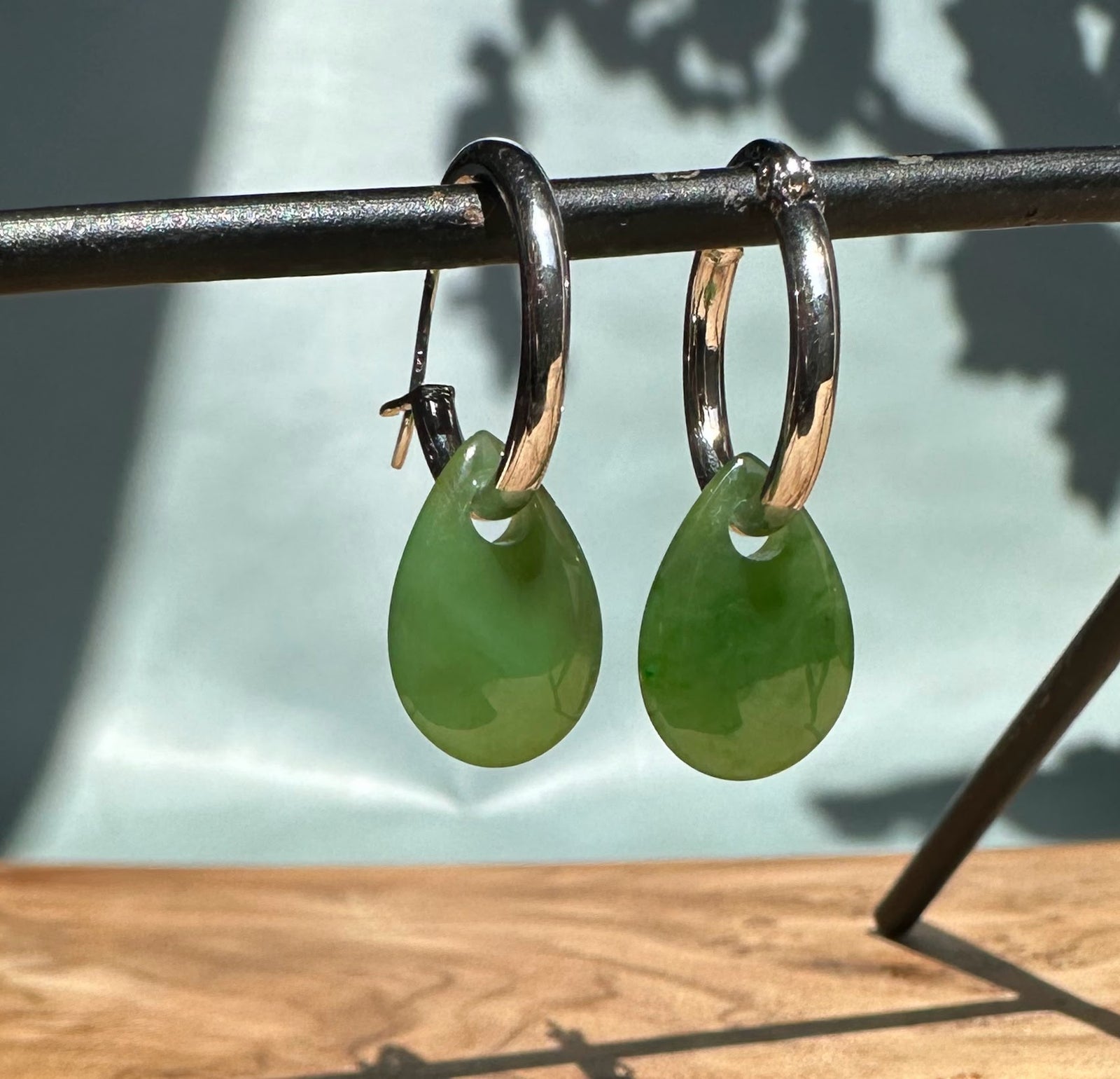 Close-up of green jade teardrop earrings on silver hoops.