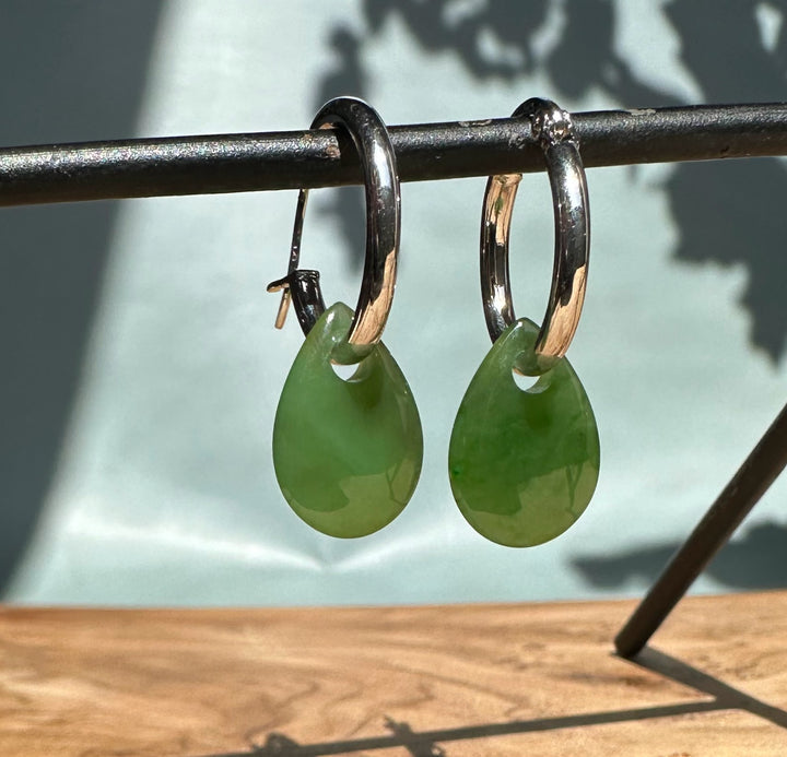 Close-up of green jade teardrop earrings on silver hoops.