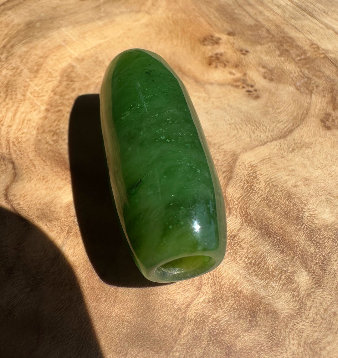 Green jade bead on a wooden surface