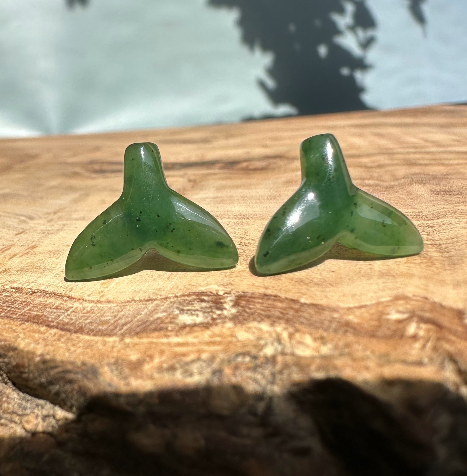 Green jade whale tail stud earrings laid side by side