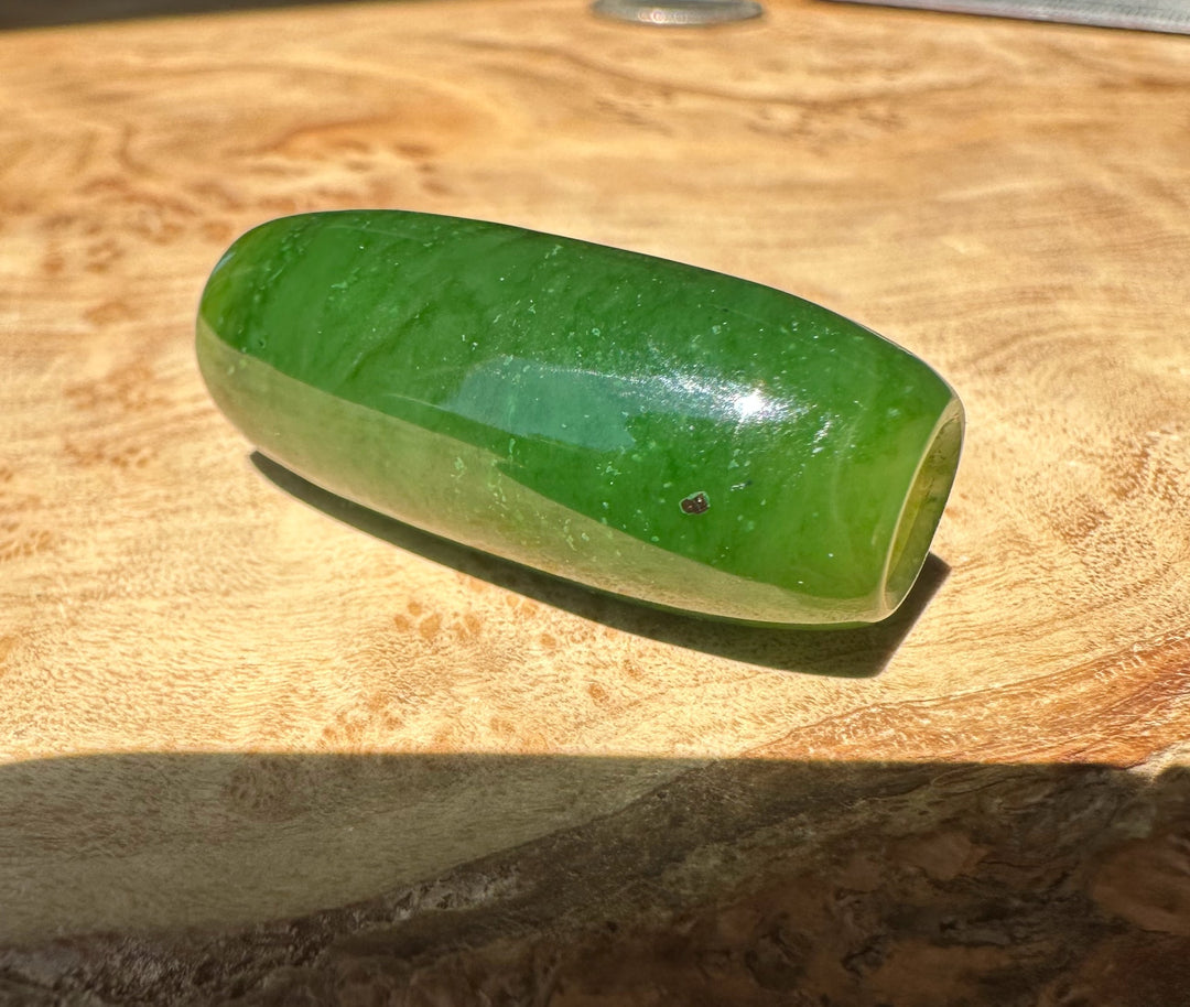 Green jade bead on a wooden surface