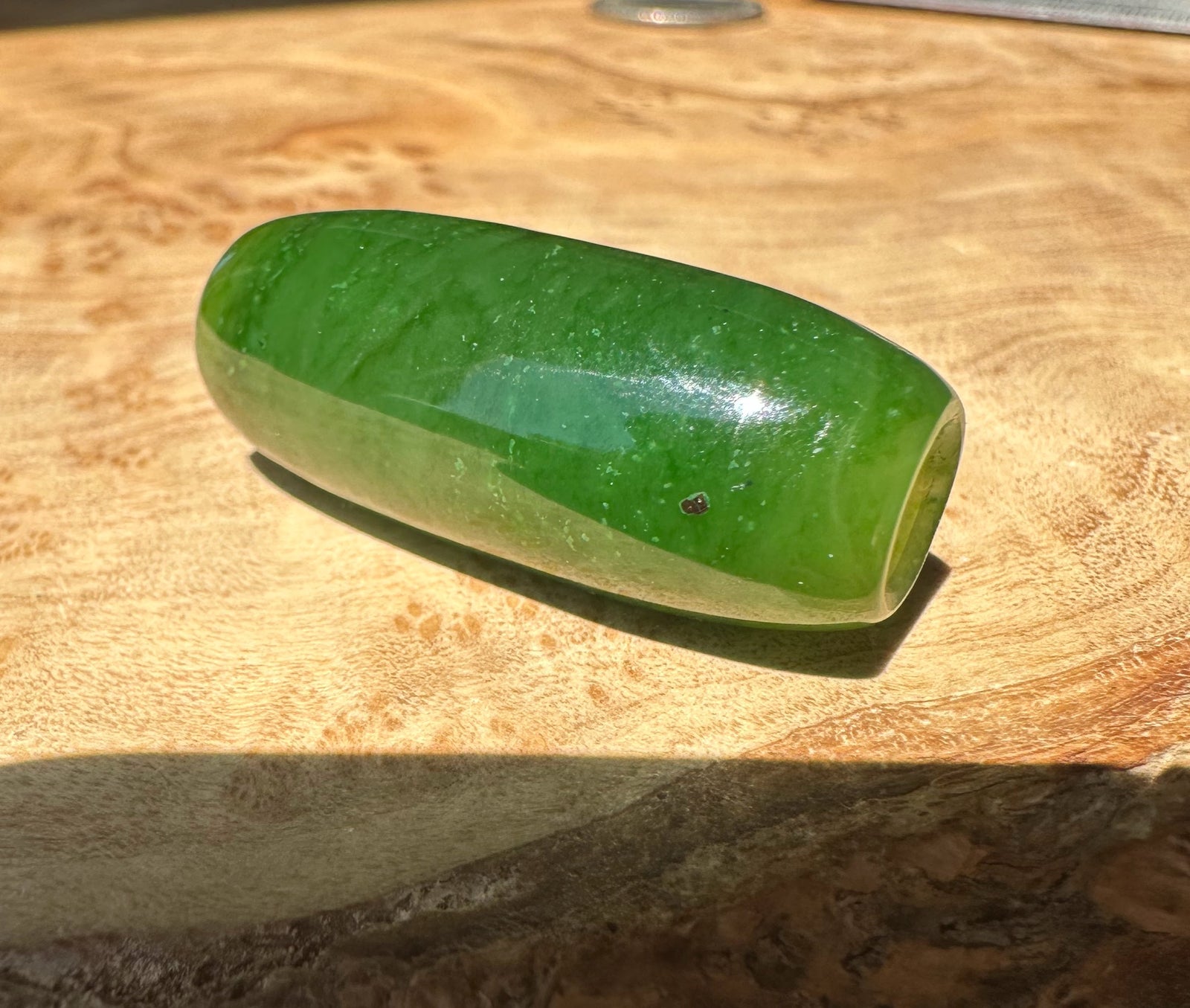 Green jade bead on a wooden surface