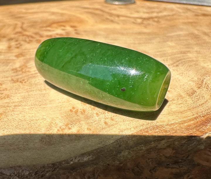 Green jade bead on a wooden surface