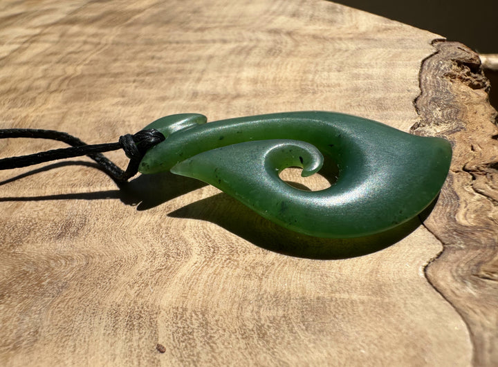 Green jade spiral pendant on a wooden surface