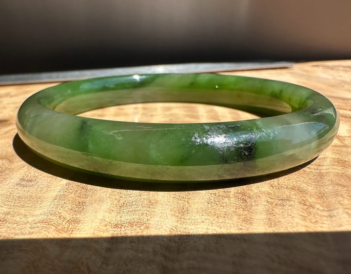 Polar green jade bangle on wooden surface