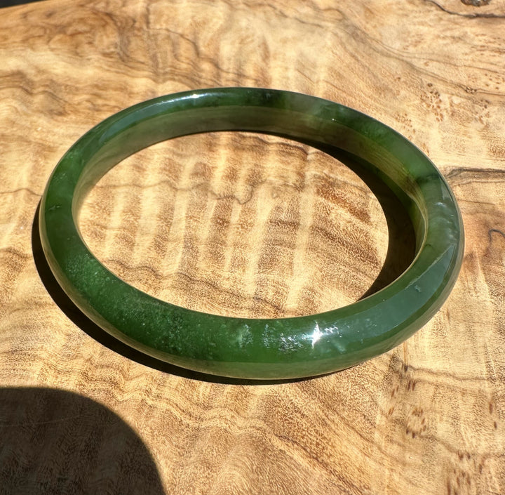 Polar green jade bangle on wooden surface