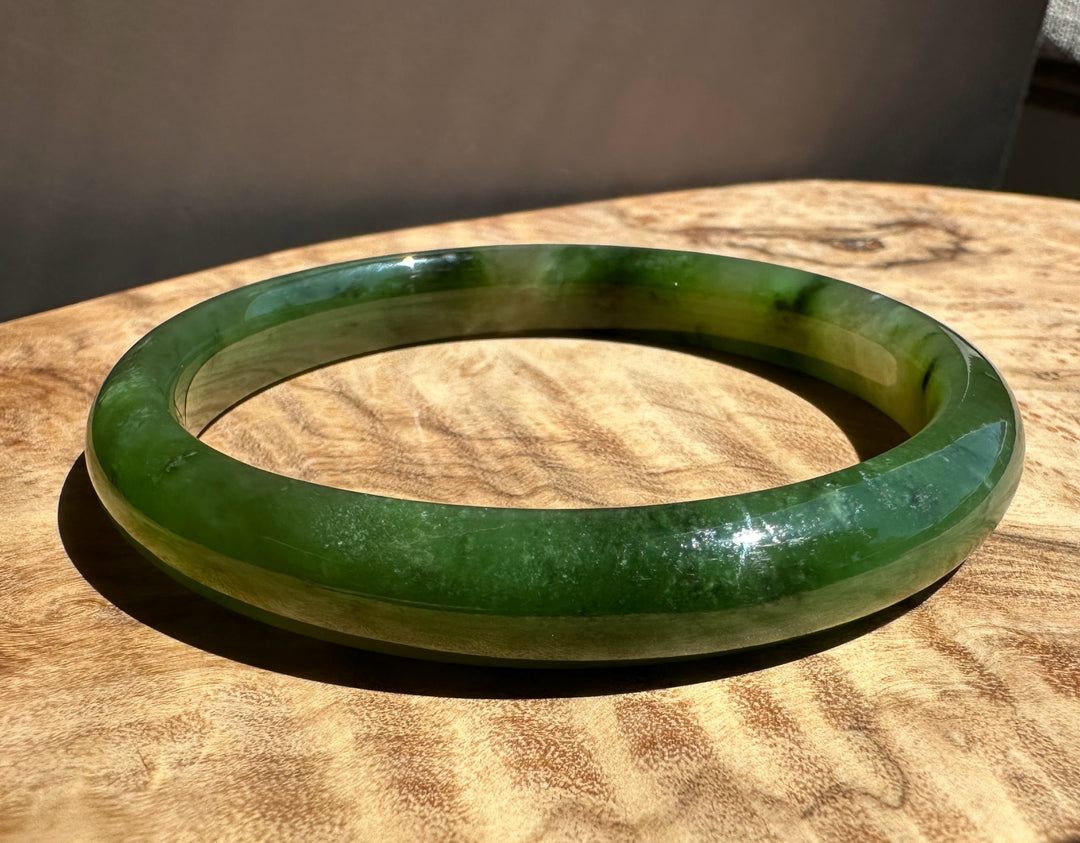 Polar green jade bangle on wooden surface