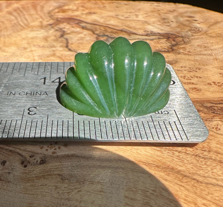 Green jade cabochon on a ruler on a wooden surface