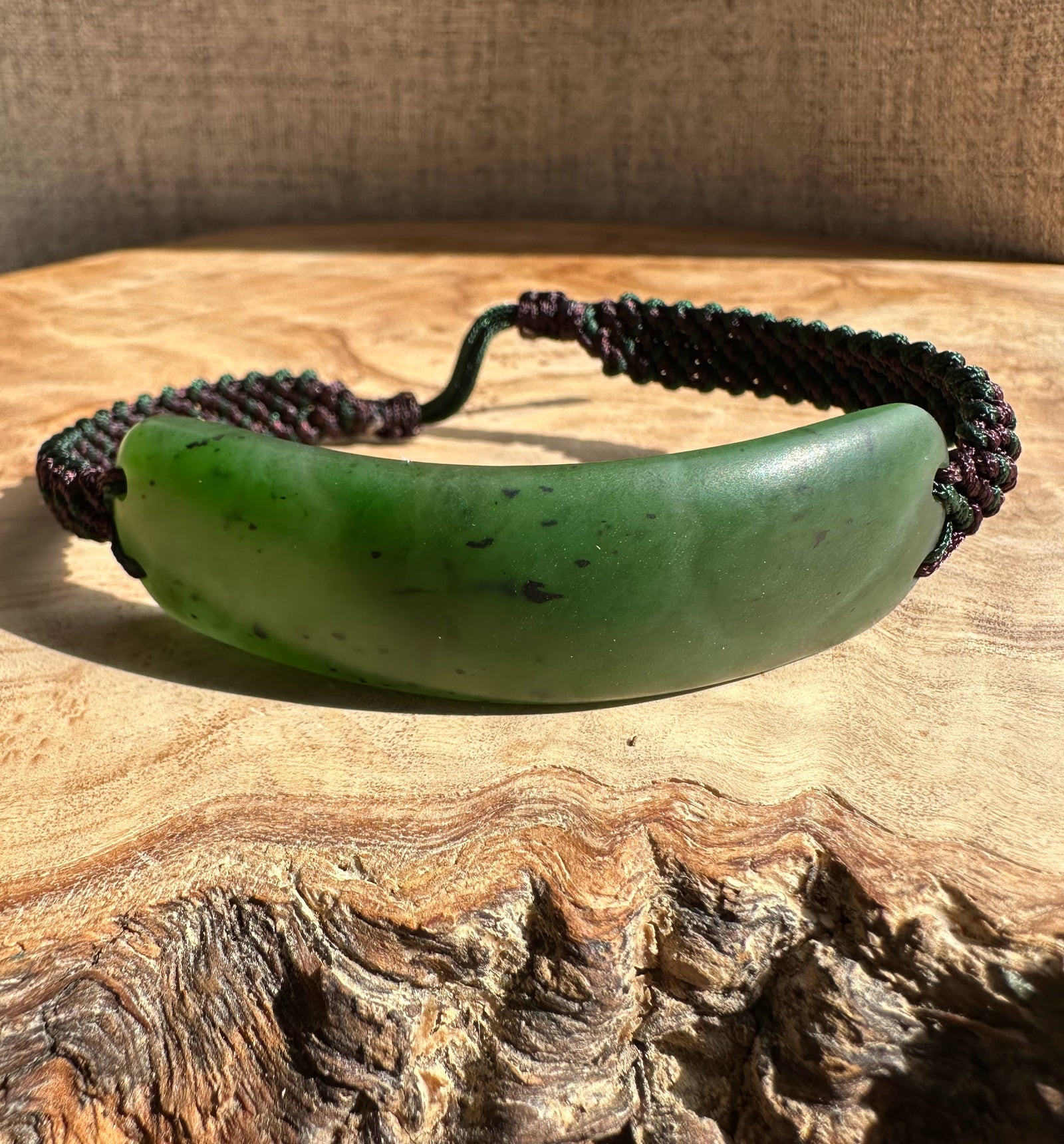 Green curved jade centerpiece on a dark braided cord men's bracelet