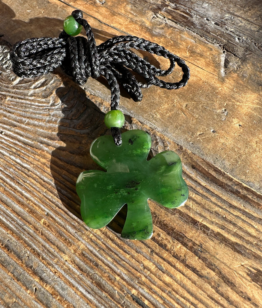 Canadian jade three leaf clover pendant on a black braided cord with two green beads