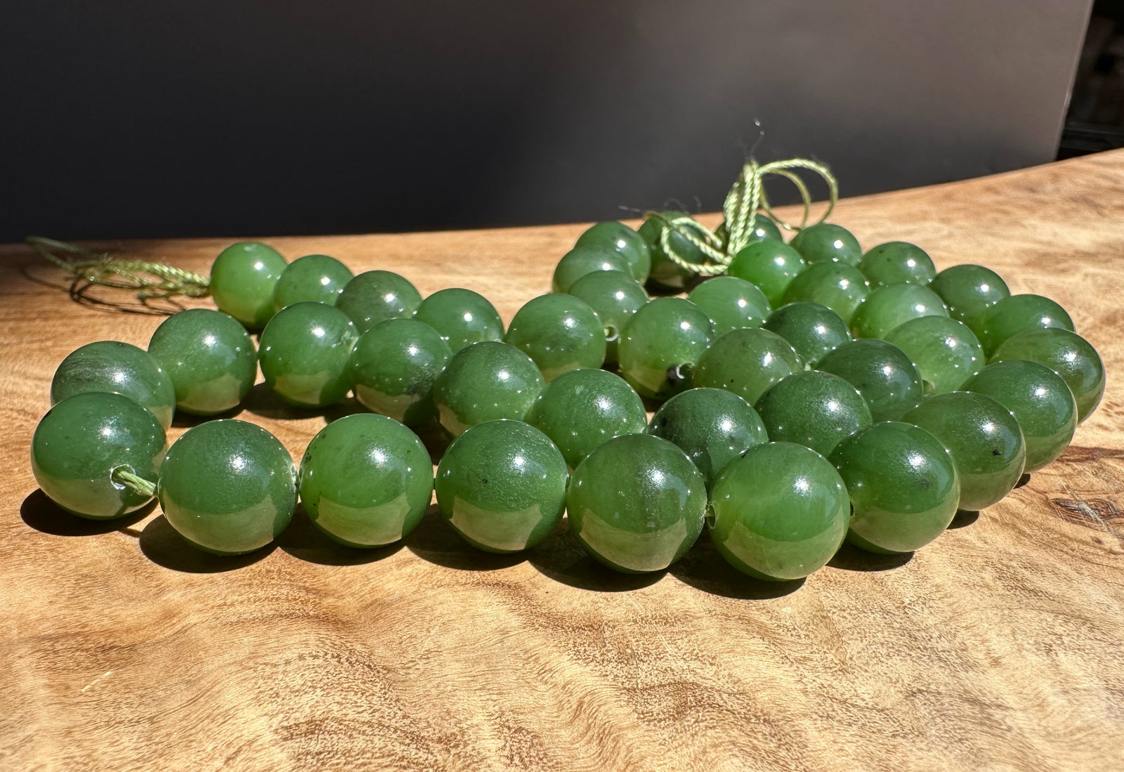 Green jade 10mm beads on a wooden surface with a dark background